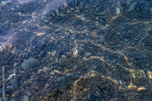 Obraz na płótnie Underwater pebble backgrounds. Colorful stones sea bottom in the sun rays. View from above through clear water. Seascape wallpaper texture. Defocus. w salonie