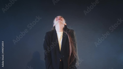Portrait of cheerful young girl playfully dancing in modern white top and stylish black trousers spreading joy.