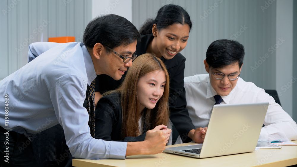 Group of happy asian business people sitting on a table raised fists cheering at laptop celebrating achievement goals to success in meeting at office Group of happy asian business people sitting on a table raised fists cheering at laptop celebrating achievement goals to success in meeting at office