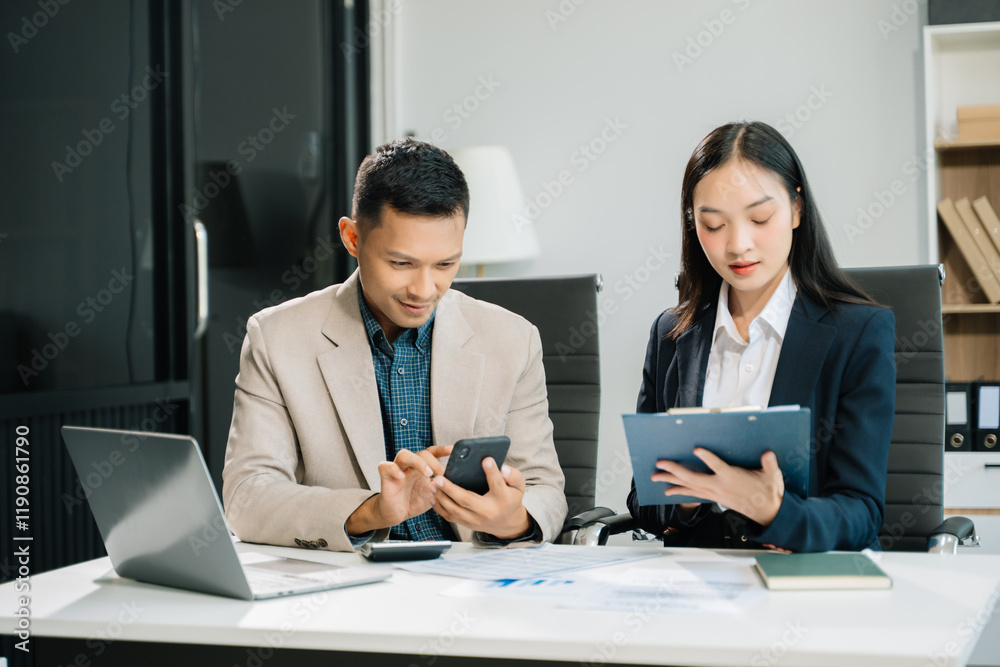 Two business workers talking on the smartphone and using laptop at the office.. Two business workers talking on the smartphone and using laptop at the office..