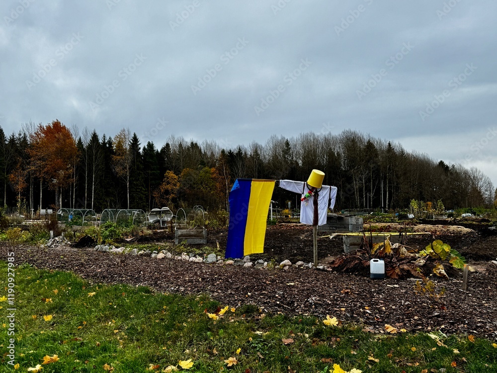 Fototapeta premium Creative scarecrow with Ukrainian flag standing amidst an autumn garden in Finland, blending culture and nature