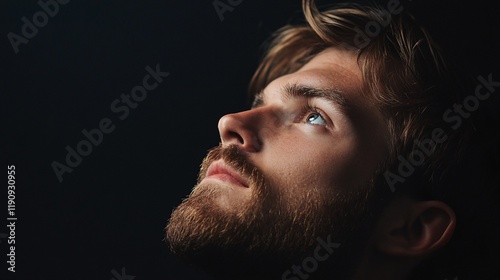 Young man looking up with hope and faith on black background
