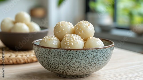 Delicious sweet dumplings served in a rustic bowl with sesame seeds on a wood...