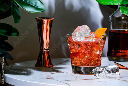 Embarcadero, an alcoholic cocktail drink with rye whiskey, gentian bitters, sweet vermouth and rind. Marble table in a lounge bar with green plants