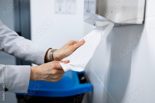 Use of paper towel after washing hands. Close up view of human hands using paper towel after hand washing in toilet.