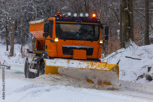 Snow plow and road salt spreader working on snowy road