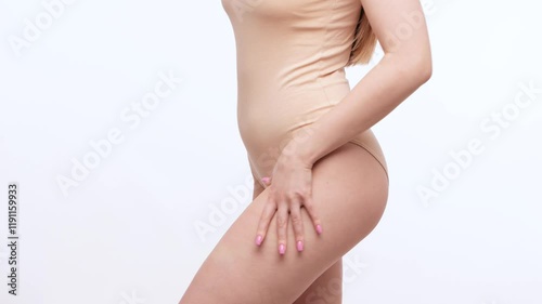 Wallpaper Mural A slender girl in beige bodysuit shows fat deposits on legs and crushes croissant on a white background. Healthy lifestyle, sport and diet. Torontodigital.ca