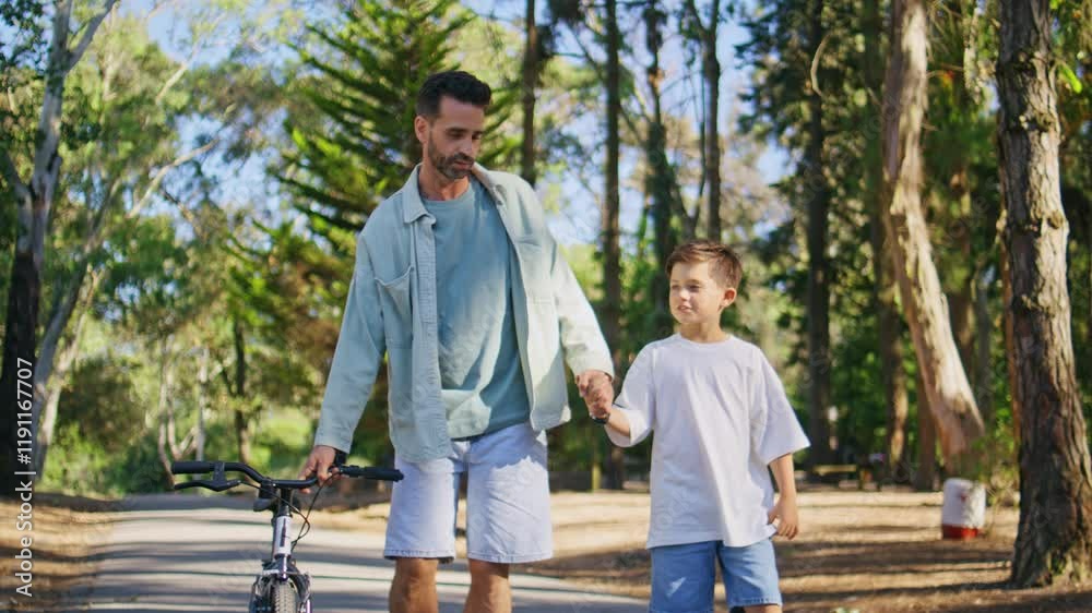 Positive family holding hands talking during walk. Man boy walking sunshine path Positive family holding hands talking during walk. Man boy walking sunshine path