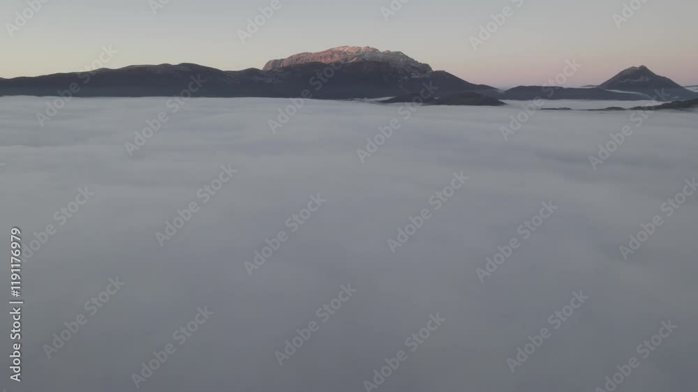 Sobrevolando bruma y nubes bajas con montaña de fondo Sobrevolando bruma y nubes bajas con montaña de fondo