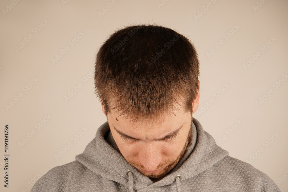 Fototapeta premium The texture of his hair is clear, and the shape of his head is emphasized. A close-up of a man's head with dark hair. This perspective gives a mysterious and contemplative feel.