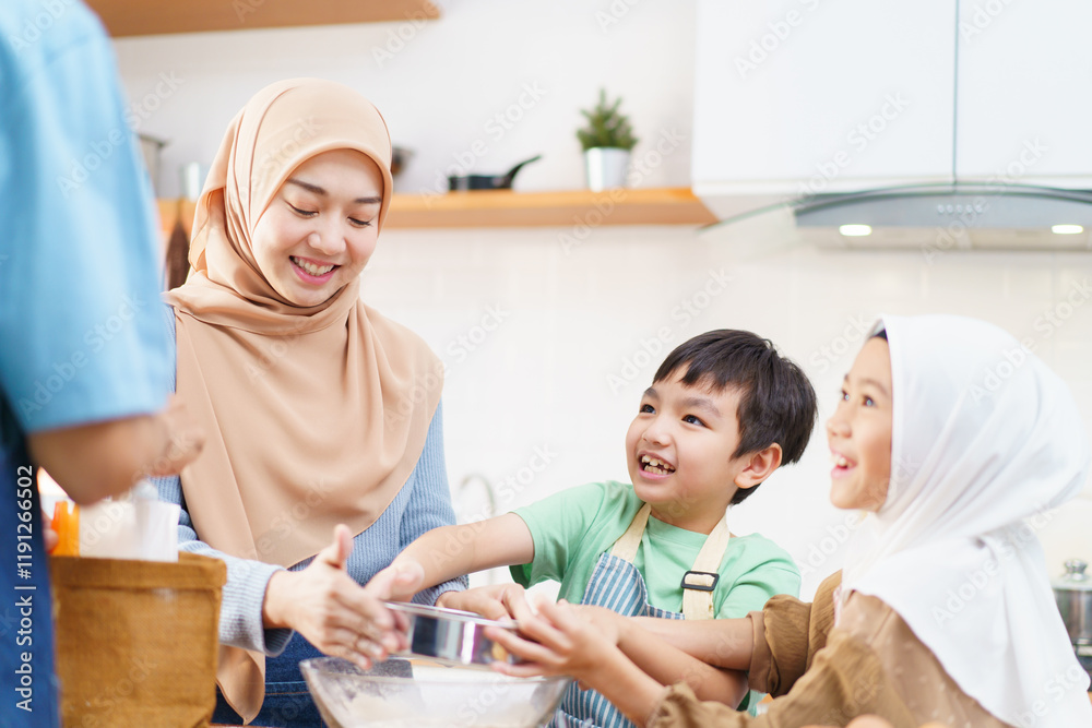 Fototapeta premium Happy Asian muslim family consisting father, mother, son, and daughter are cooking together in the kitchen.