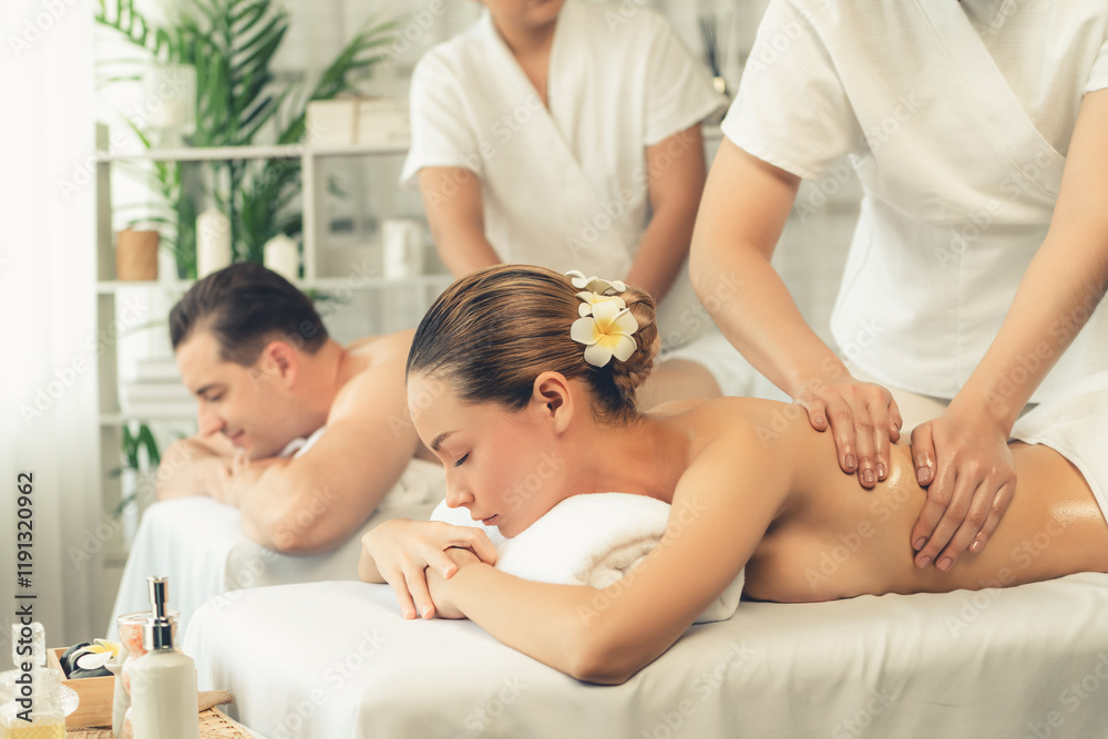 Obraz premium Caucasian couple customer enjoying relaxing anti-stress spa massage and pampering with beauty skin recreation leisure in day light ambient salon spa at luxury resort or hotel. Quiescent