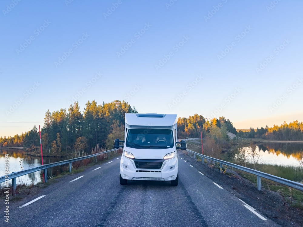 Obraz premium Motorhome driving on a scenic road in Kiruna, Sweden, with autumn foliage and beautiful lake views.
