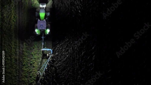 Night Farming: Drone View of Tractor Plowing Field with Stunning Lighting Contrast