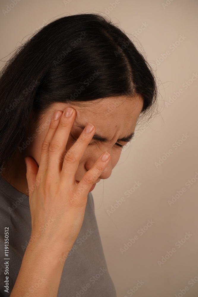 The woman touches her temple with one hand, signaling the agony of a bad headache. Her posture emphasizes the discomfort. The scene focuses on the need for pain management and alleviation. The woman touches her temple with one hand, signaling the agony of a bad headache. Her posture emphasizes the discomfort. The scene focuses on the need for pain management and alleviation.