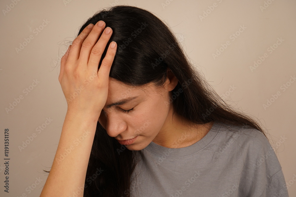 Her posture and expression reflect self-recognition. The photo captures a genuine moment of realization. The girl touches her head with both hands, signaling the acknowledgment of a mistake. Her posture and expression reflect self-recognition. The photo captures a genuine moment of realization. The girl touches her head with both hands, signaling the acknowledgment of a mistake.