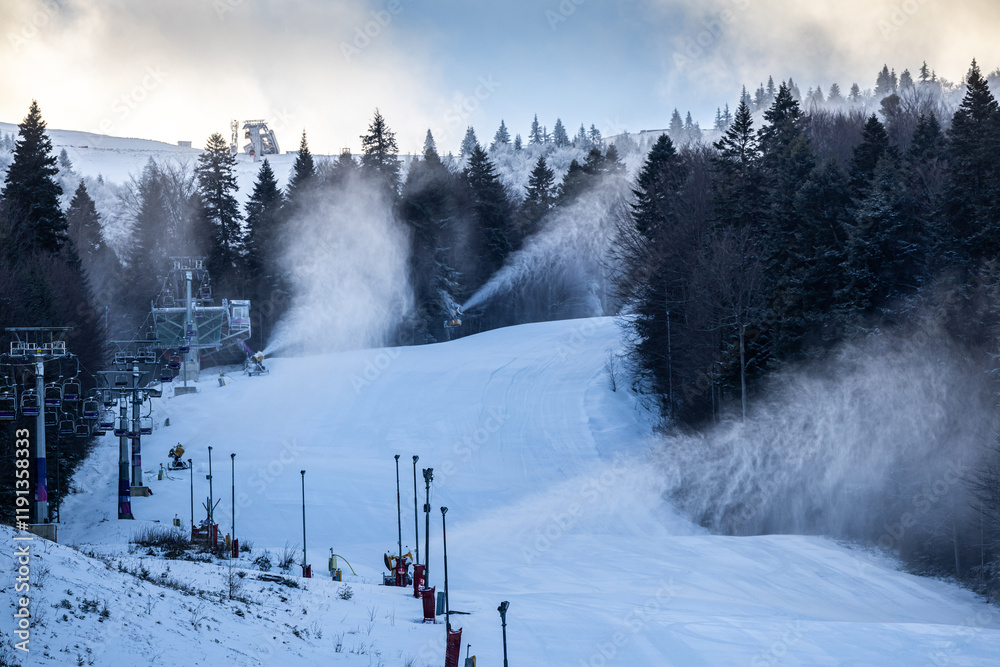 Ski resort. Empty ski slopes in the early morning with snow making machines powered on to create more snow. Snow cannon at winter sports resorts.