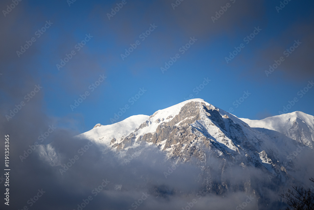 Winter in the Romanian mountains. Beautiful view through the clouds to Bucegi Mountains, next to Busteni, Azuga, Sinaia and Predeal mountain ski resorts. Travel and hike to Romania.