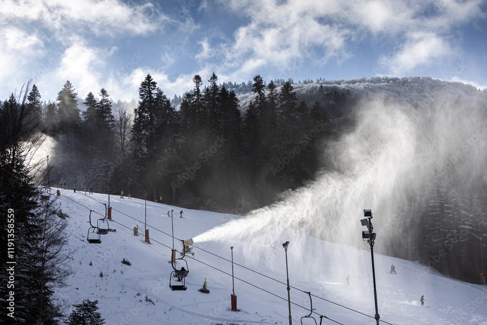 Snow making in a mountain resort. Beautiful view with snow cannons powered on to create snow from water and to keep the slopes available for tourists.