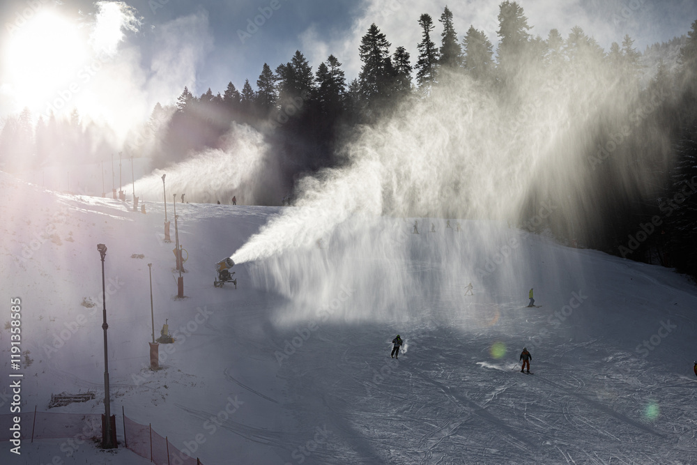Snow making in a mountain resort. Beautiful view with snow cannons powered on to create snow from water and to keep the slopes available for tourists.