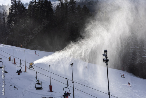 Obraz na płótnie Winter ski resort. Beautiful view with clouds of snow created by the snow cannon machine. Tourist skiing on slopes. Winter sports. w salonie