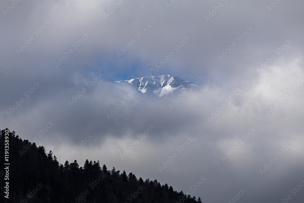 Winter in the Romanian mountains. Beautiful view through the clouds to Bucegi Mountains, next to Busteni, Azuga, Sinaia and Predeal mountain ski resorts. Travel and hike to Romania.