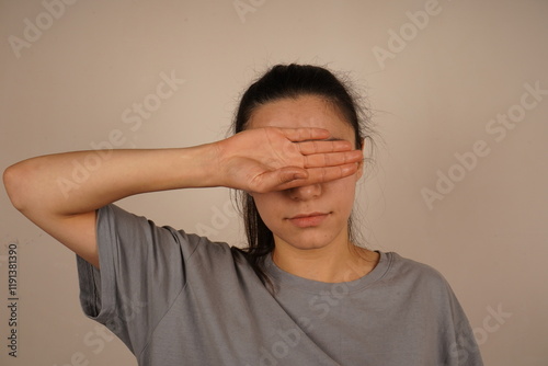 This action symbolizes the moment of escape from an irresistible situation. The gesture indicates an unwillingness to face the truth. The woman covered her eyes with her hands. photo