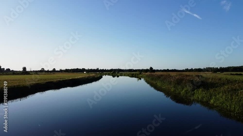  View of a Beautiful  River at Sunset Surrounded by Green Fields Drone Aerial 4K Slow Motion