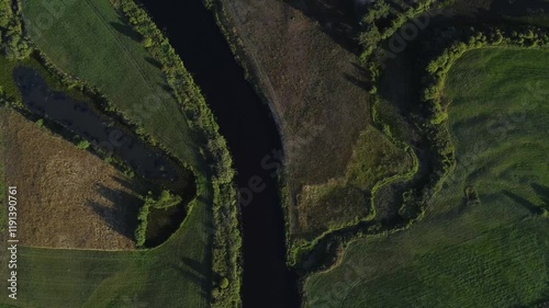  View of a Beautiful  River at Sunset Surrounded by Green Fields Drone Aerial 4K Slow Motion