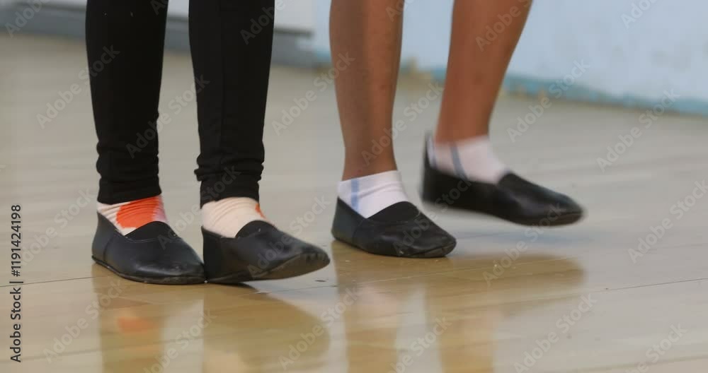 A close-up view of several pairs of feet wearing black dance shoes and white socks on a light, polished dance floor. Some of the socks have small pops of color, with one pair featuring an orange accen A close-up view of several pairs of feet wearing black dance shoes and white socks on a light, polished dance floor. Some of the socks have small pops of color, with one pair featuring an orange accen