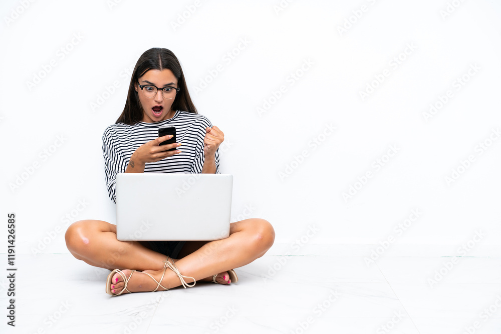 Young caucasian woman with a laptop sitting on the floor surprised and sending a message Young caucasian woman with a laptop sitting on the floor surprised and sending a message