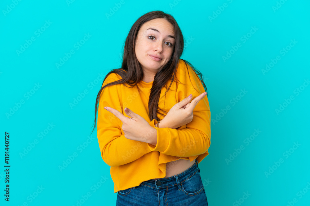 Young Ukrainian woman isolated on blue background pointing to the laterals having doubts Young Ukrainian woman isolated on blue background pointing to the laterals having doubts