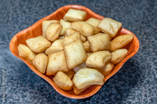 Side view of the national pastries of the peoples of Central Asia - boorsok (baursak), these are plump square dough products fried in vegetable oil, they lie in a wooden square plate. photo