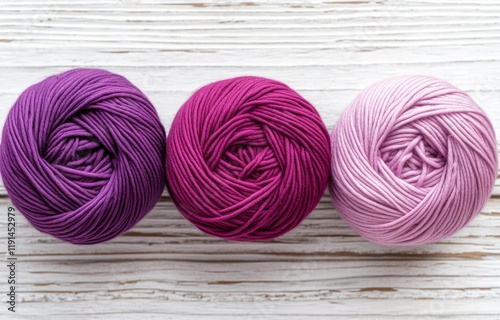 Three bundles of yarn for knitting attire or other pieces: two light purple and one dark purple, against a light-hued background photo