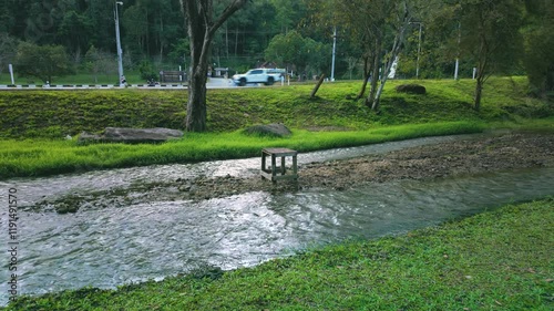 Bench in the Middle of Stream in Forested Mountains with Passing Car
