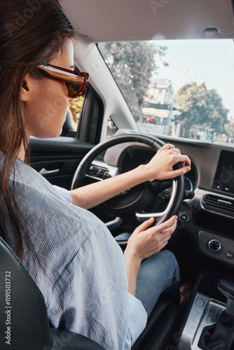 Woman, glasses, driving, car, smartphone a woman wearing glasses is driving a car with her hands on the steering wheel, her eyes focused on the screen of her smartphone, showcasing distracted driving photo