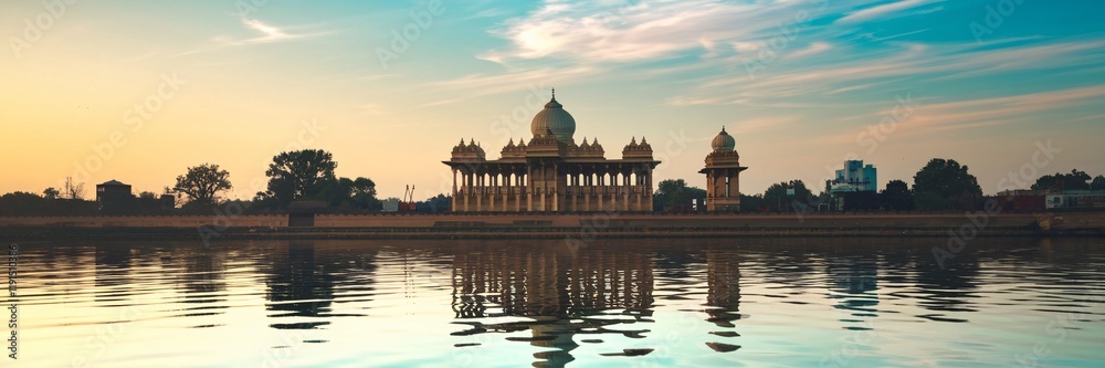Fototapeta premium Sunrise over a grand palace reflected in calm water.