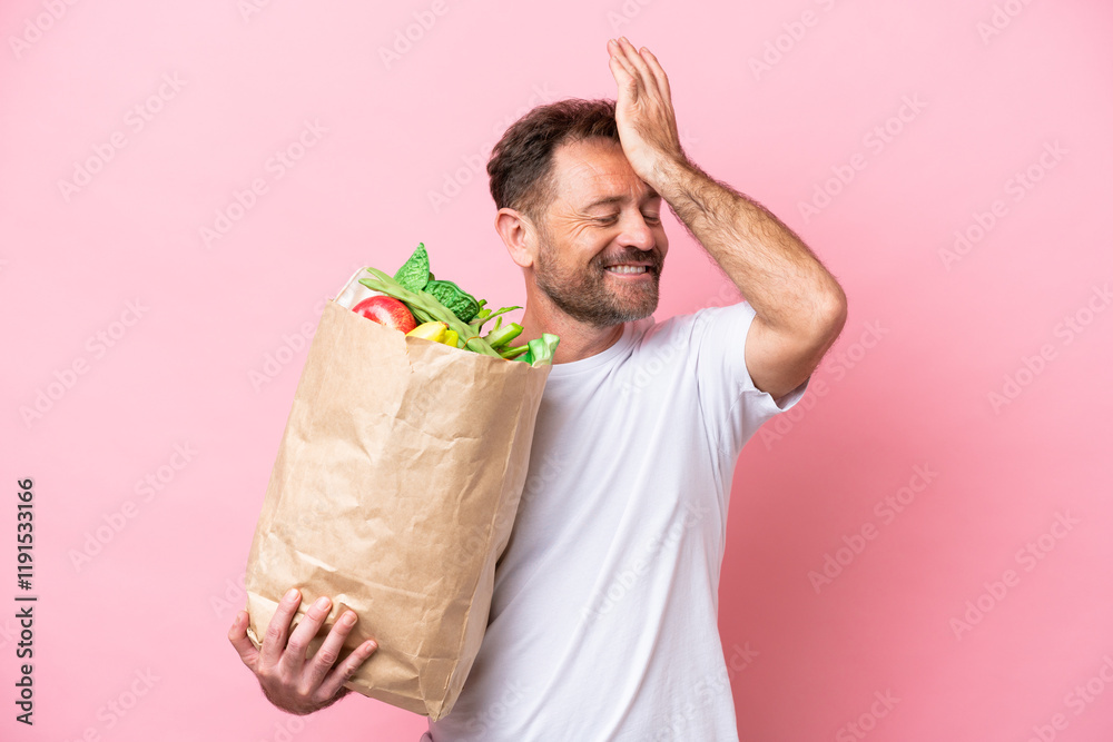 Middle age man holding a grocery shopping bag isolated on pink background has realized something and intending the solution Middle age man holding a grocery shopping bag isolated on pink background has realized something and intending the solution