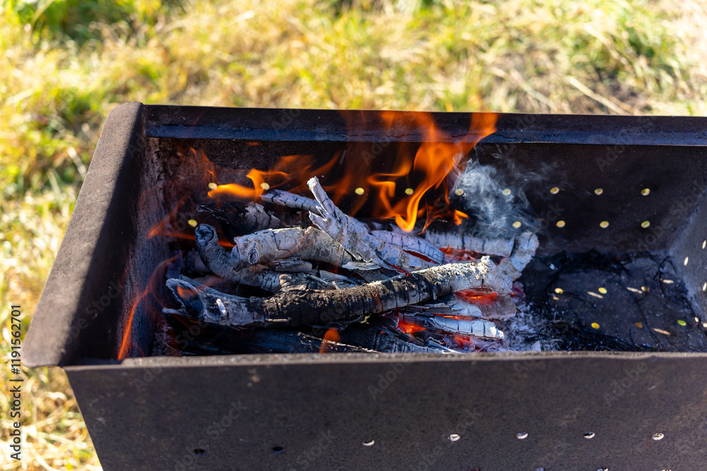 Charcoal igniting in a grill during a sunny outdoor gathering Charcoal igniting in a grill during a sunny outdoor gathering