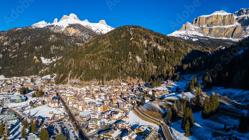 Canazei, a picturesque alpine town in the Dolomites, offers stunning winter landscapes and world-class ski facilities. Surrounded by snow-capped peaks and captured by drone photo