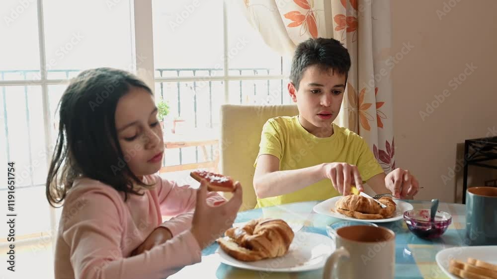 Brother and Sister Enjoying a Simple Breakfast of Croissants and Jam Brother and Sister Enjoying a Simple Breakfast of Croissants and Jam