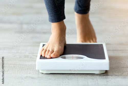 Unrecognizable young Indian woman stepping on scales to measure her weight at home, closeup of feet. Cropped view of millennial lady checking result of her slimming diet. Healthy living concept