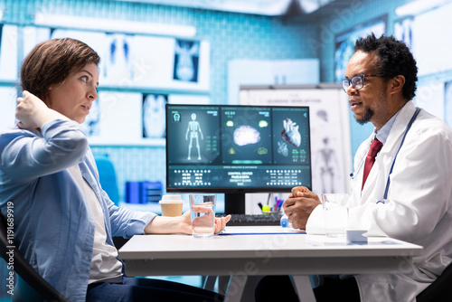 Female patient listening to a diagnostic report from doctor based on MRI scan results and x ray imaging, pointing at computer in medical cabinet. African american expert gives assistance. photo