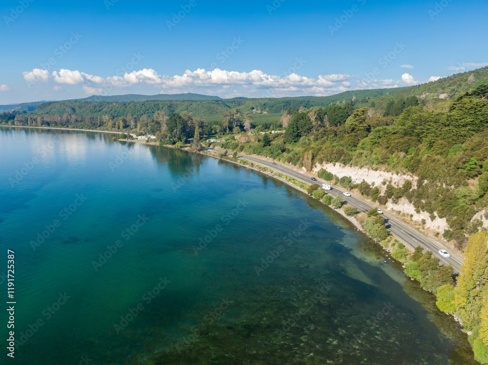 Obraz premium Aerial view of a scenic Lake Taupo road. Cars travel along the highway bordering the clear turquoise water. Tranquil landscape. LAKE TAUPO, TURANGI, WAIKATO, NEW ZEALAND