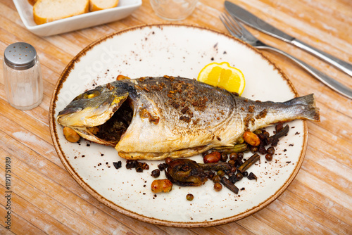 Appetizing roasted dorada served with stewed eggplant and bell pepper garnished photo