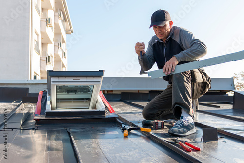 A roofer builder worker finishing folding a metal sheet using special pliers with a large flat grip. A roofer and window master work.  House improvement under construction concept