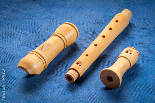 components of wooden recorder flute instrument, classic German style, against textured art paper photo