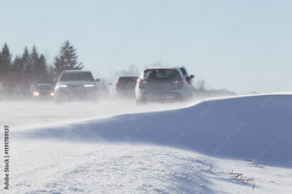 Cars drive along snow-covered roads with directional arrow signs against a clear blue sky. Cars drive along snow-covered roads with directional arrow signs against a clear blue sky.