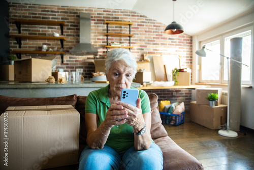 Senior woman on phone reviewing paperwork at home with moving boxes photo