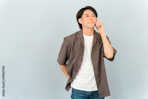 スマホ・スマートフォンを持って電話・通話する若いアジア人男性（話す・会話）
 photo